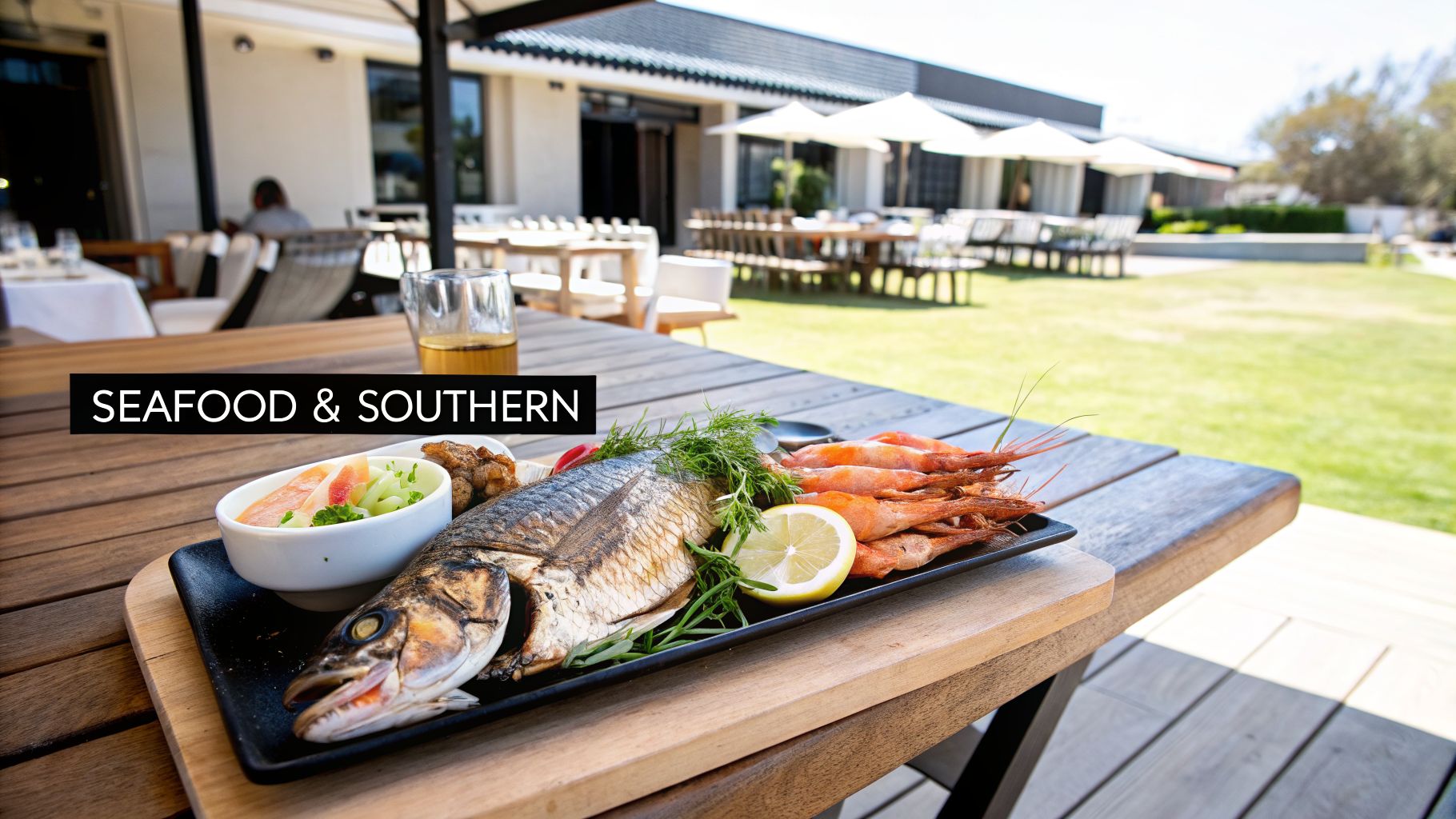 A delicious seafood platter with grilled fish, prawns, and a side dish at an outdoor restaurant.