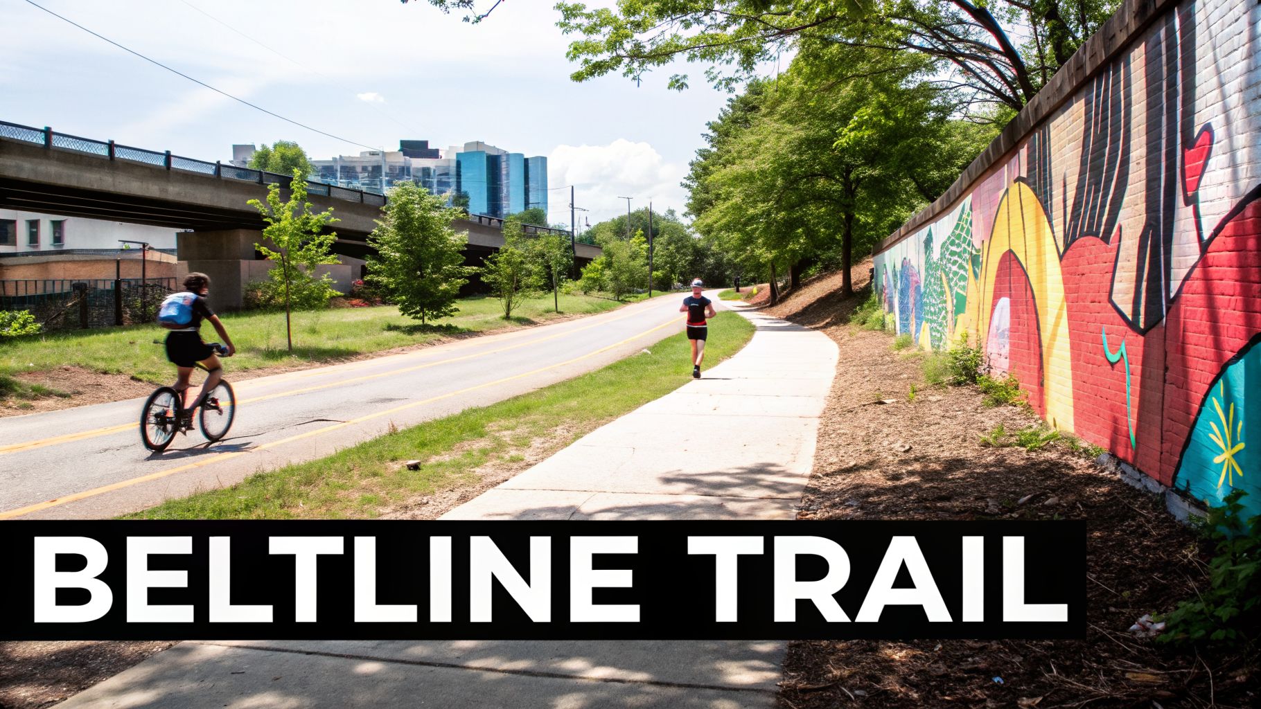 People biking and running on the Atlanta BeltLine Trail with vibrant mural art and city skyline in the background.